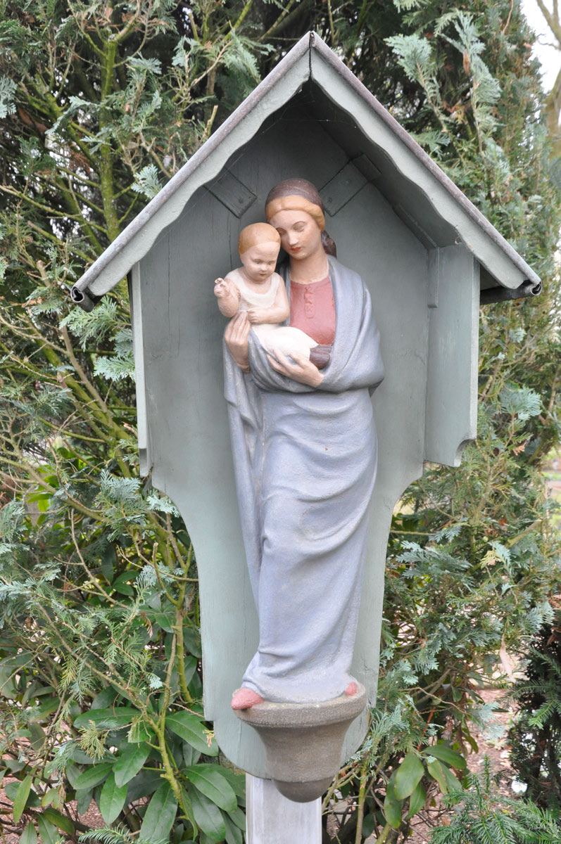 Die Holzgruppe „ Maria mit Kind“ entstand 1922 in der Werkstatt Mormann und schmückt die Familiengrabstätte Mormann