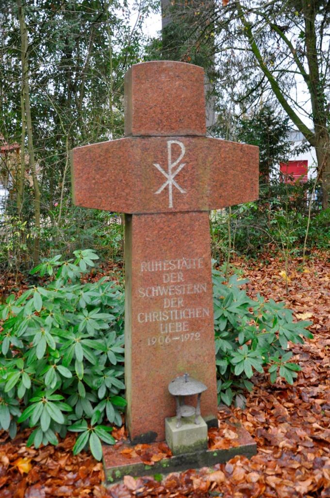 Ein Kreuz aus rosa Granitstein steht jetzt am Ende der Grabreihen an der Stelle, an der sich zuvor die Totenkapelle des Friedhofs befand.